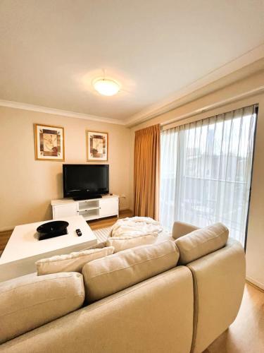 a living room with a couch and a television at 10 CBD Resort 2BR Secure Suite Pool Gym & Parking in Perth