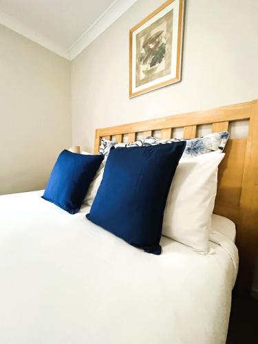 a bedroom with a bed with blue and white pillows at 10 CBD Resort 2BR Secure Suite Pool Gym & Parking in Perth