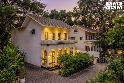 a large white house with yellow doors at StayVista at Casa Roma - Private Pool in Siolim