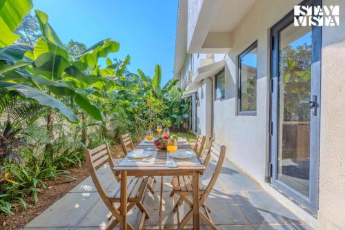 a wooden table with chairs on a patio at StayVista at Casa Roma - Private Pool in Siolim