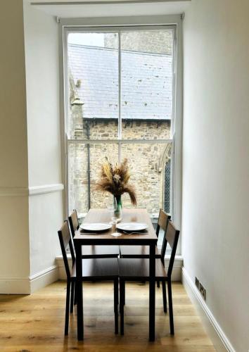 a dining room table with chairs and a window at 2 Historic Tenby Tourist Favourite -Steps to Beach in Pembrokeshire