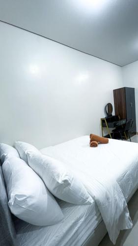 a white bed in a room with a white wall at Comfortable Studio Stay Made for Relaxation in Iloilo City