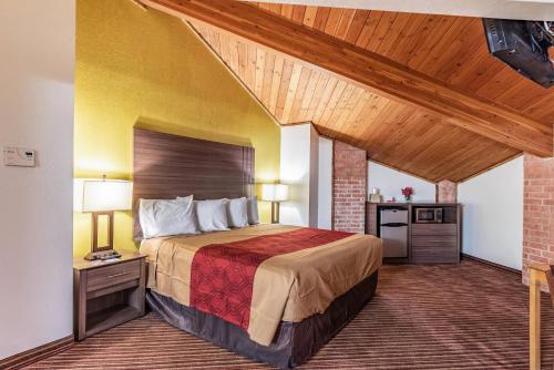 a hotel room with a bed and a wooden ceiling at Econo Lodge Inn & Suites Mckinney - Plano North in McKinney