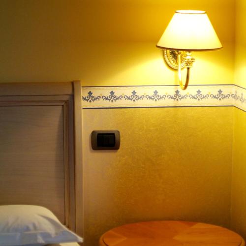 a lamp on a wall next to a bed at Hotel Ristorante Novecento in Pegognaga