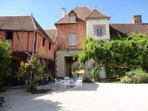 een huis met een tafel en stoelen op de binnenplaats bij Chateau Des Roises in Bucey-en-Othe