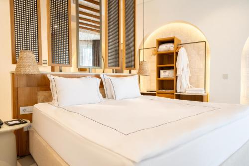 a large white bed in a room with a mirror at The Norm Collection Door'a Bodrum in Torba
