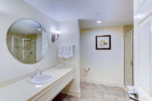 Baño blanco con lavabo y espejo en Turtle Cay Resort, en Virginia Beach