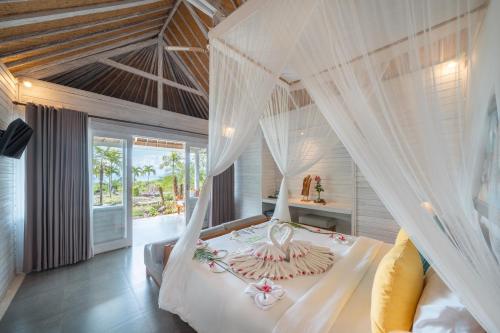 a bedroom with a white bed with a canopy at Bukit Taman Cottages in Nusa Lembongan