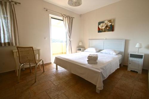 a bedroom with a bed and a chair and a window at Agios Nikitas View in Agios Nikitas