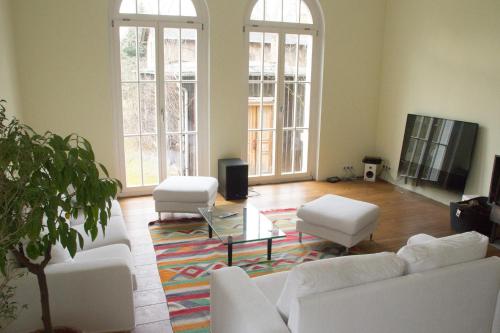 a living room with white couches and a tv at Villa Erica in Teltow