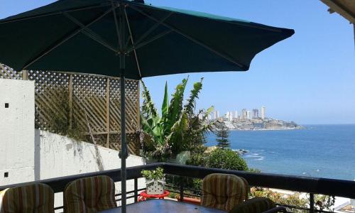 a table with an umbrella on a balcony overlooking the ocean at Apartamento en Edificio Las Arenas in Concón