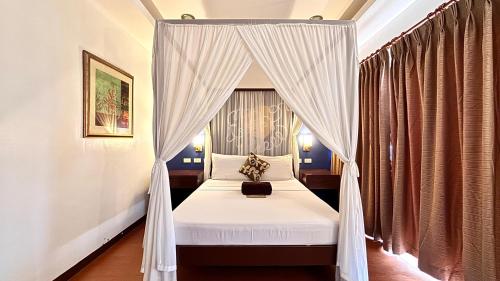 a bedroom with a canopy bed with curtains at Hotel Palacio Puerto Princesa in Puerto Princesa City