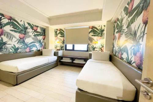 a room with two beds and a window with tropical wallpaper at Mella Hotel Manila near NAIA Airport in Manila