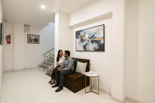 a man and woman sitting on a couch in a room at FabHotel Apple Near ITI in Indore