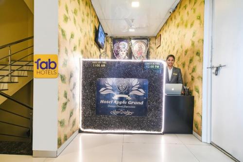 a woman standing at a desk in a room with a wall at FabHotel Apple Near ITI in Indore
