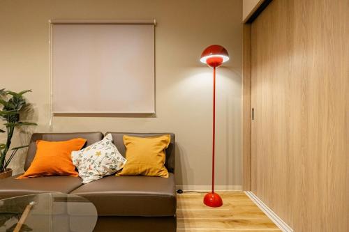 a red floor lamp next to a couch with pillows at Lino Stay Kasai 'elua in Tokyo