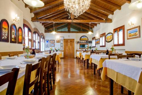 een eetkamer met tafels en stoelen en een kroonluchter bij Agriturismo Villa Mocenigo in Mirano