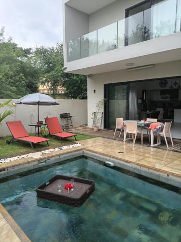 a house with a pool with a table and chairs at Mira lune guesthouse in Flic-en-Flac