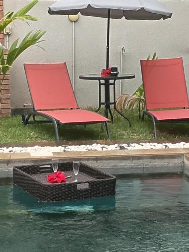 a table and two chairs and an umbrella in the water at Mira lune guesthouse in Flic-en-Flac