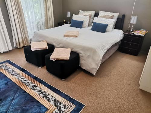 a bedroom with a large bed with two ottomans at Green Hills Farm House in Drummond