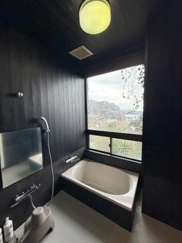 a bathroom with a bath tub and a window at 伊豆ベース73 in Higashiizu
