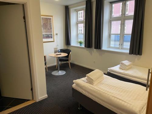 a room with two beds and a table and a window at Hotel Aarhus City Apartments in Aarhus