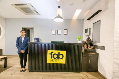 a woman standing next to a table with a yellow sign at FabHotel Dev Palace I - Pitampura in New Delhi