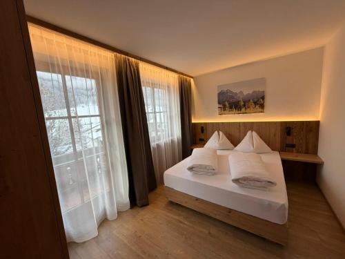 a bedroom with a white bed and a large window at Appartements Michael in Sesto