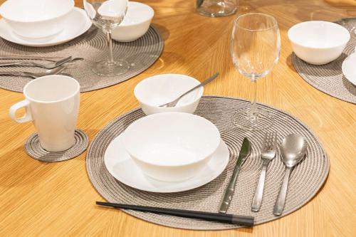 a wooden table with white plates and silverware on it at Lino Stay Kasai 'ekol in Tokyo