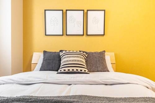 a bed with four pictures on a yellow wall at Lino Stay Kasai 'ekol in Tokyo