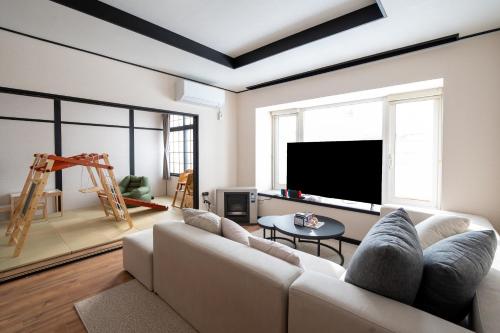 a living room with a couch and a flat screen tv at Biei Sakura Stay in Biei