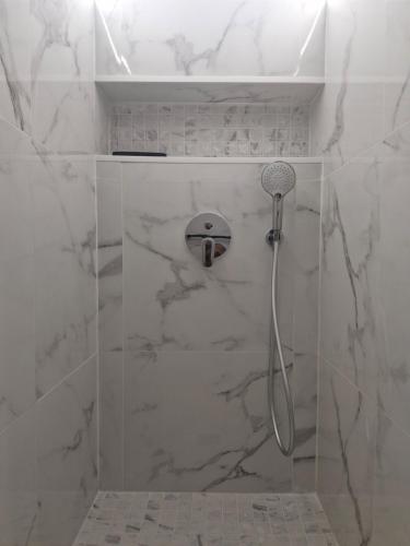 a bathroom with a shower with white marble walls at L'écrin des hauts in Saint-Denis