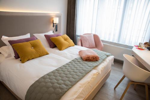 a bedroom with a large bed with colorful pillows at ABC Hotel in Blankenberge