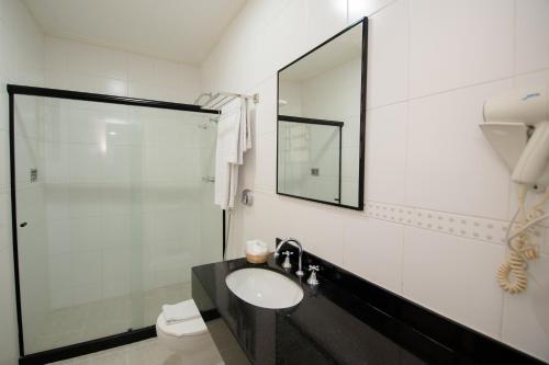 a bathroom with a sink and a shower with a mirror at Hotel OK in Rio de Janeiro
