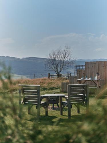 two park benches and a table with a view of the water at Tomnauld Farm in Pitlochry