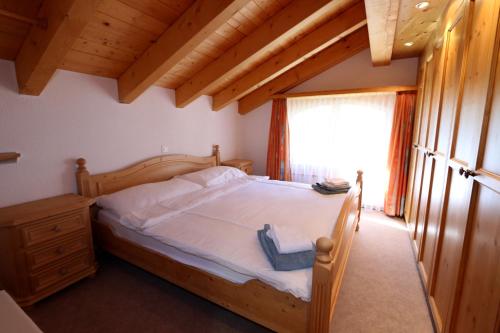 a bedroom with a bed with a wooden frame and a window at Dominic A in Saas-Fee