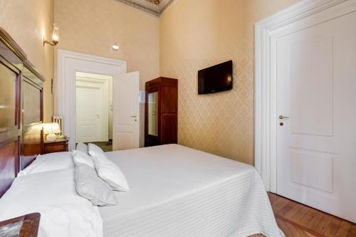 a bedroom with a white bed and a tv on the wall at Affreschi Su Roma Luxury B&B in Rome
