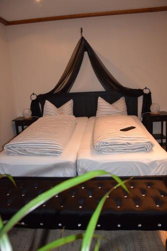 ein Bett mit einem schwarzen Kopfteil und einem Telefon darauf in der Unterkunft Ferienwohnung Könitz in Naumburg