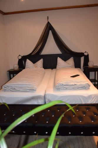 a bed with a black headboard and a phone on it at Ferienwohnung Könitz, Ricarda in Naumburg