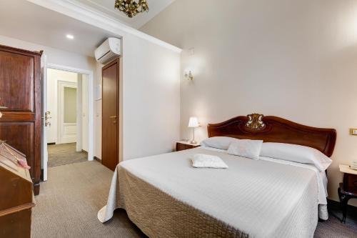 a bedroom with a white bed with a wooden headboard at Affreschi Su Roma Luxury B&B in Rome