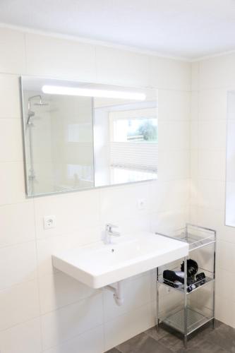 a white bathroom with a sink and a mirror at Ferienwohnung Köchl in Münster