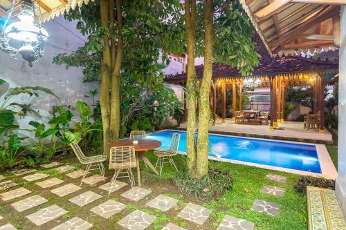a patio with a table and chairs next to a pool at Villa Omah Rindu in Yogyakarta