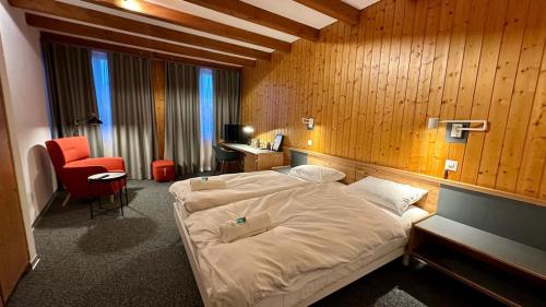 a bedroom with a bed and a desk and a chair at Hotel du Cheval Blanc in Nods