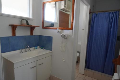 a bathroom with a sink and a blue shower curtain at Ocean View Motel Bowen in Bowen