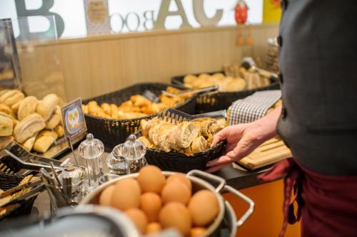 a person holding a basket of bread and eggs on a buffet at Book Hotel Leipzig in Leipzig