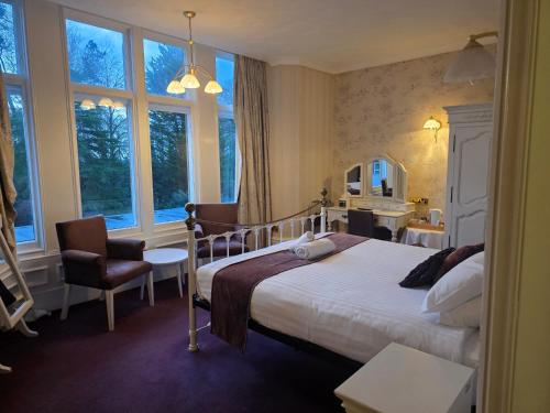 a bedroom with a bed and a chair and a mirror at Oaklands Hall Hotel Grimsby in Laceby