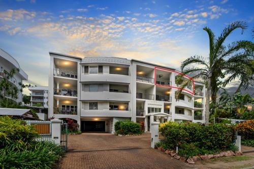 a white apartment building with a palm tree at Relax at Trinity in Trinity Beach