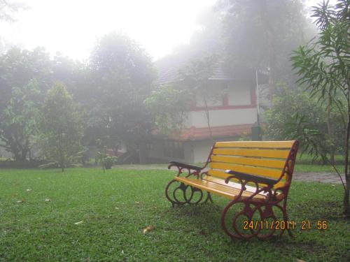 a wooden bench sitting in the grass in a park at Greenwoods Resort, Thekkady in Thekkady