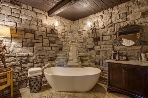 a bathroom with a bath tub and a stone wall at Storybook Riverside Inn in Leavenworth