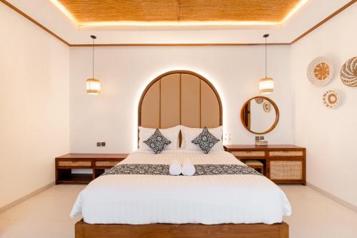 a bedroom with a large bed with two tables and a mirror at Green Mutiara Jimbaran in Jimbaran